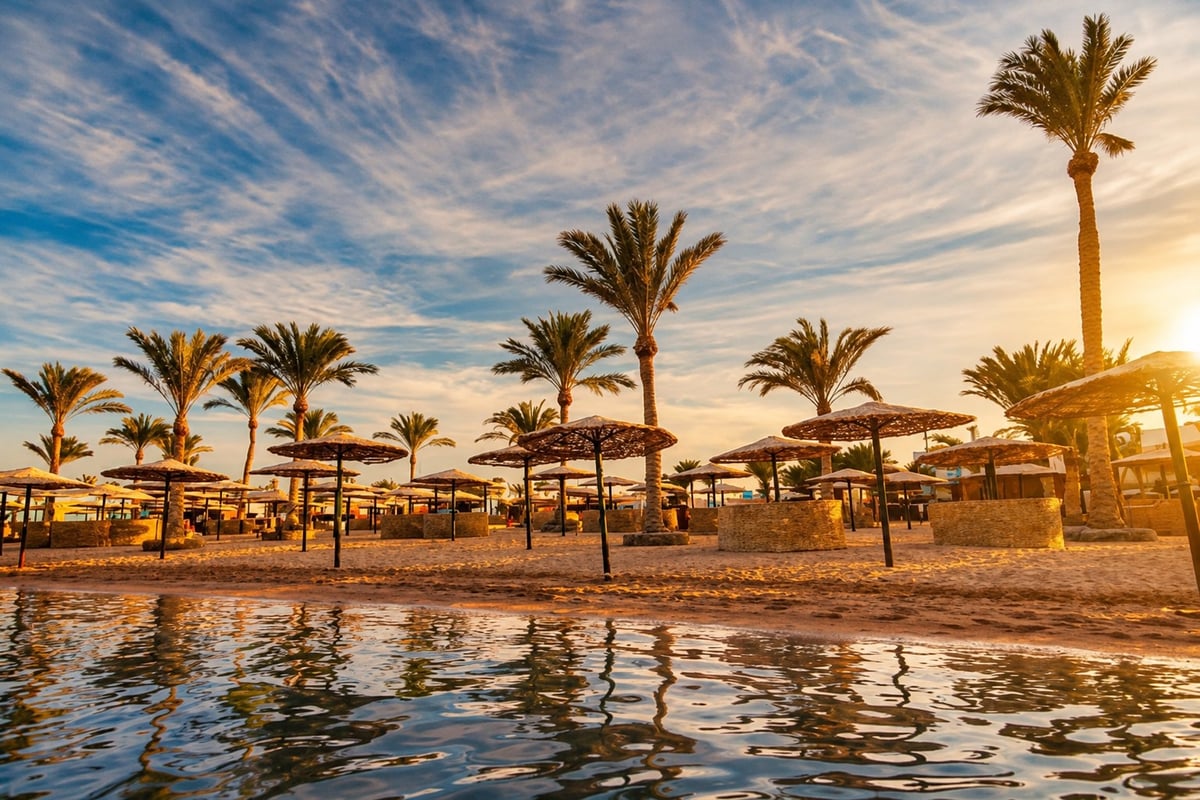 Hurghada beachfront at sunrise, palm trees and straw parasols mirrored on the Red Sea, Hurghada hotel to airport transfer