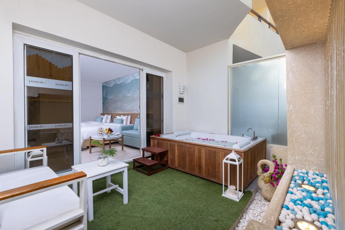 Amwaj Oyoun Resort terrace with a bathtub and glass shower.