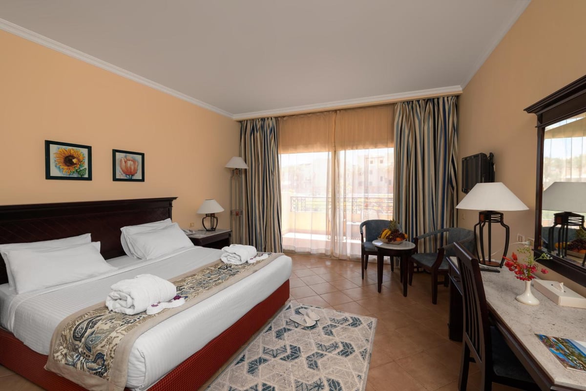 Amwaj Oyoun Resort bedroom with a large bed and sliding glass doors.