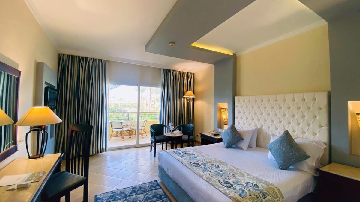 Amwaj Oyoun Resort bedroom with a tufted headboard and sliding glass doors.