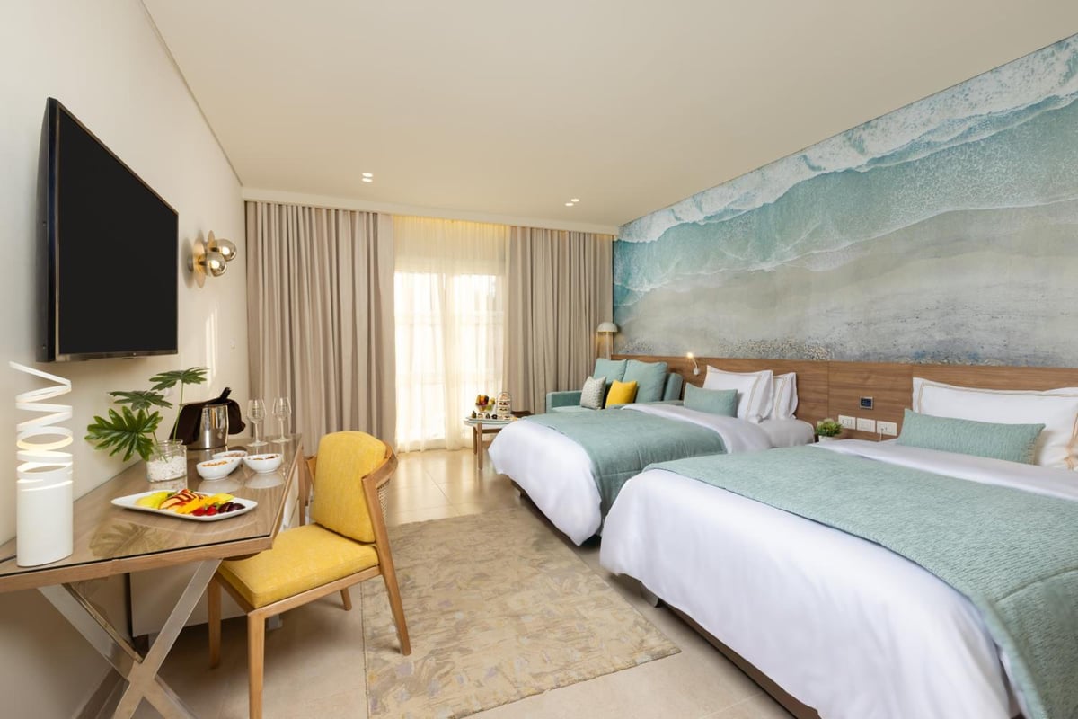 Amwaj Oyoun Resort twin bedroom with twin beds and a wave mural.