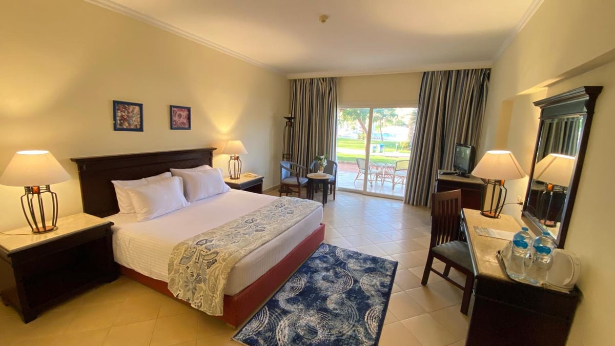 Amwaj Oyoun Resort guest room with a large bed and sliding glass doors.