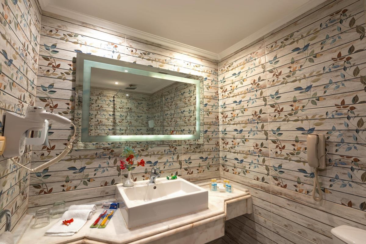 Amwaj Oyoun Resort bathroom with a vessel sink and patterned tile walls.