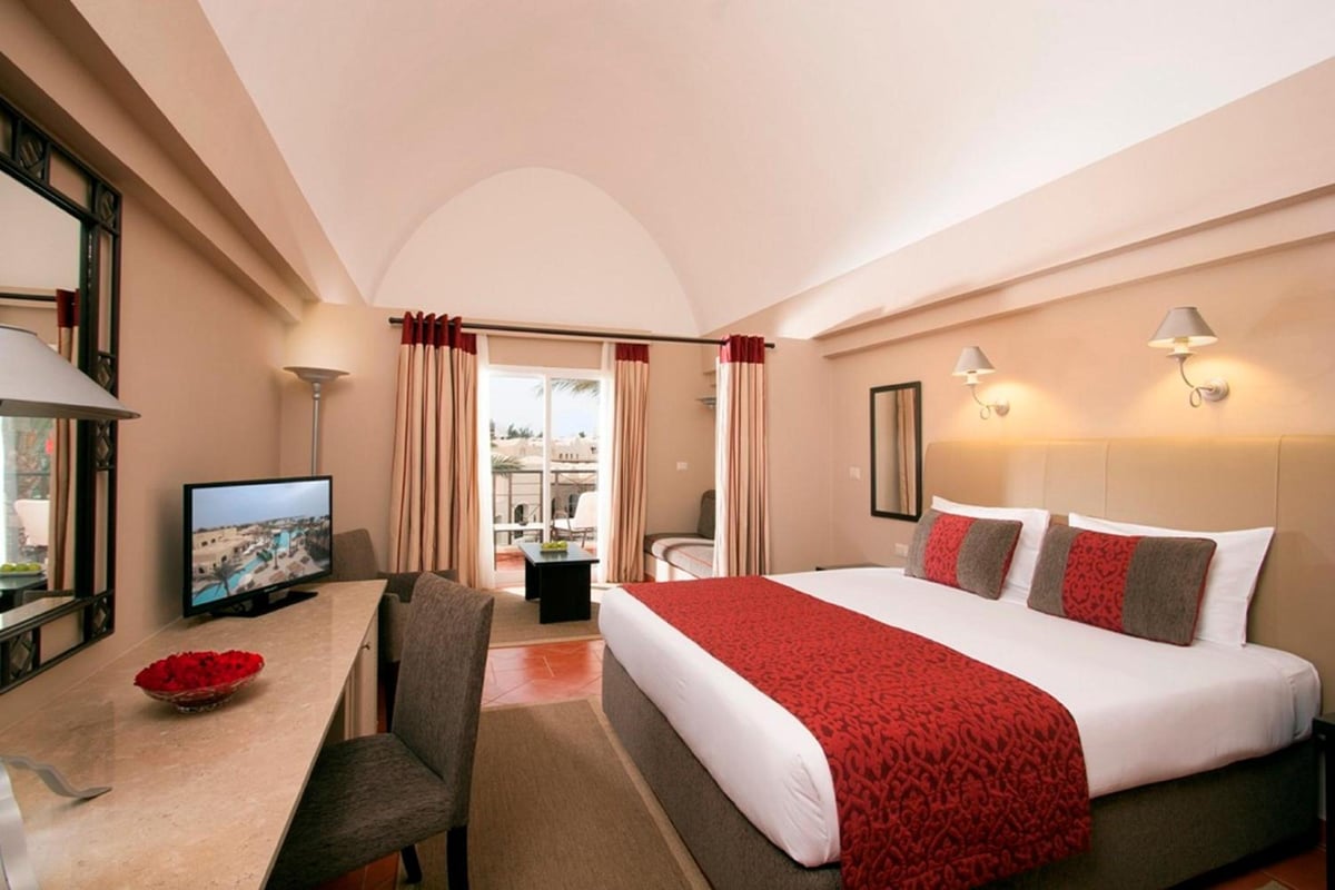 JAZ Makadina bedroom with an arched ceiling and a red bed runner.