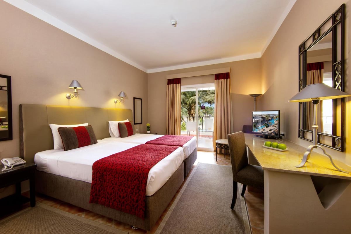 JAZ Makadina guest room with a bed and balcony doors.