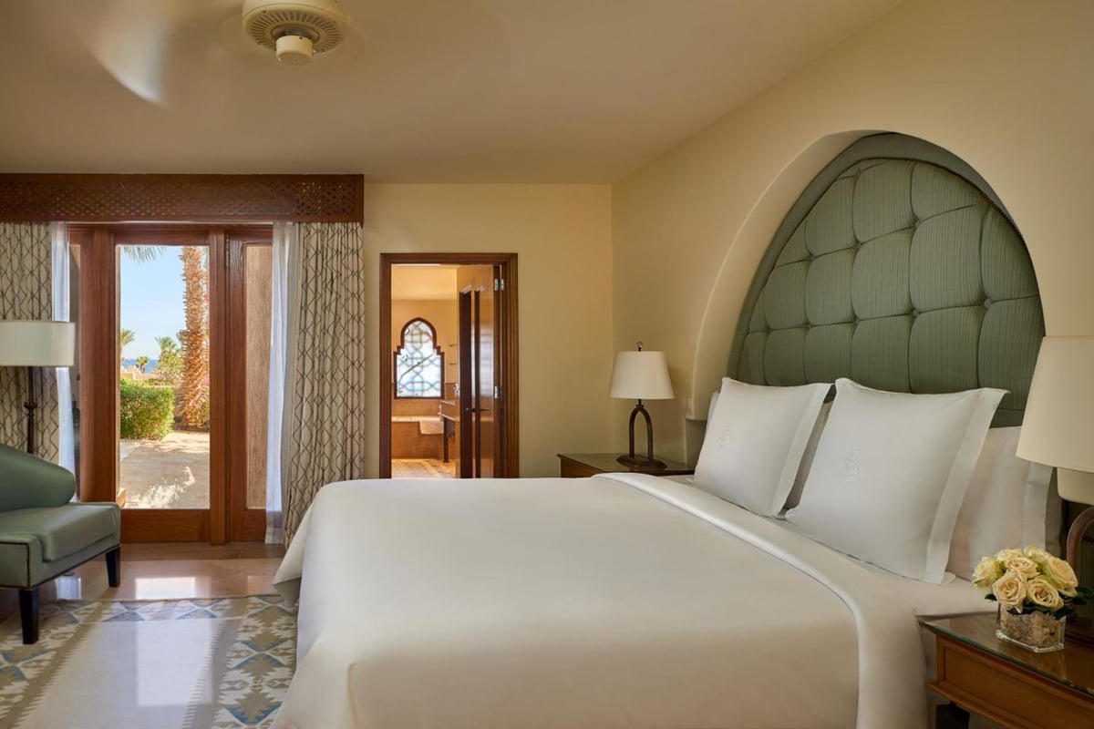 Four Seasons Resort Sharm El Sheikh bedroom with an arched headboard and glass doors.