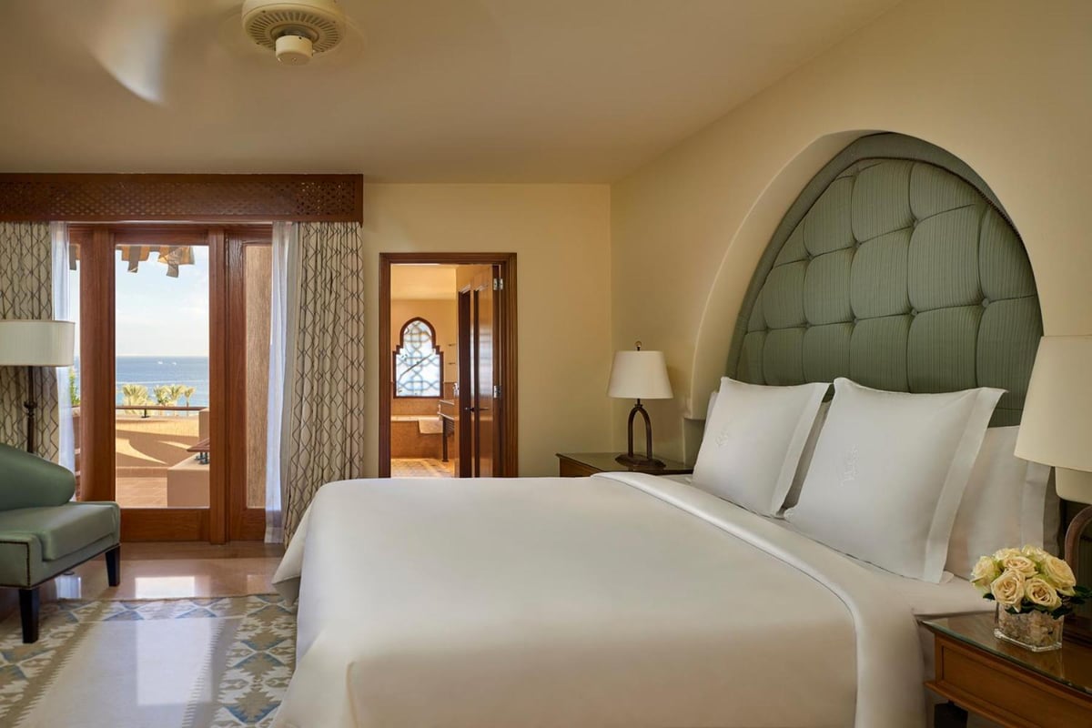 Four Seasons Resort Sharm El Sheikh bedroom with a white bed and arched headboard.