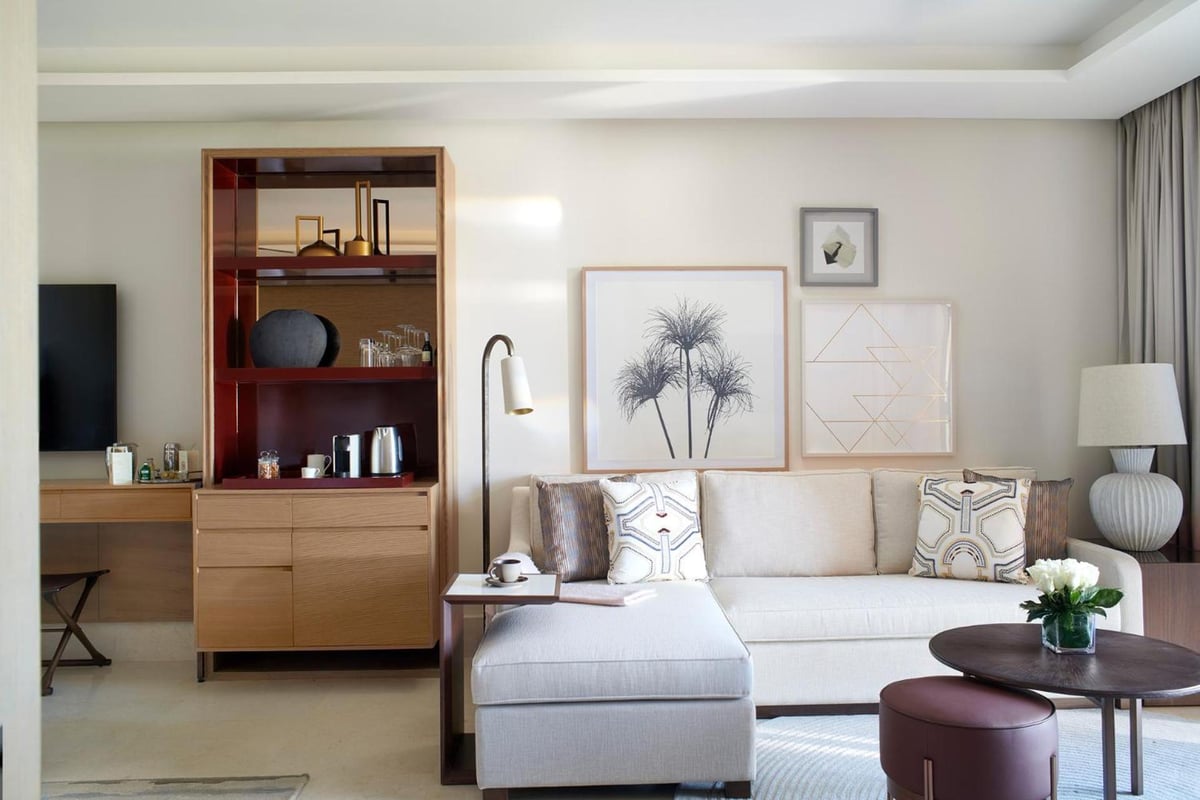 Four Seasons Resort Sharm El Sheikh suite living area with a sectional sofa and wooden shelving.