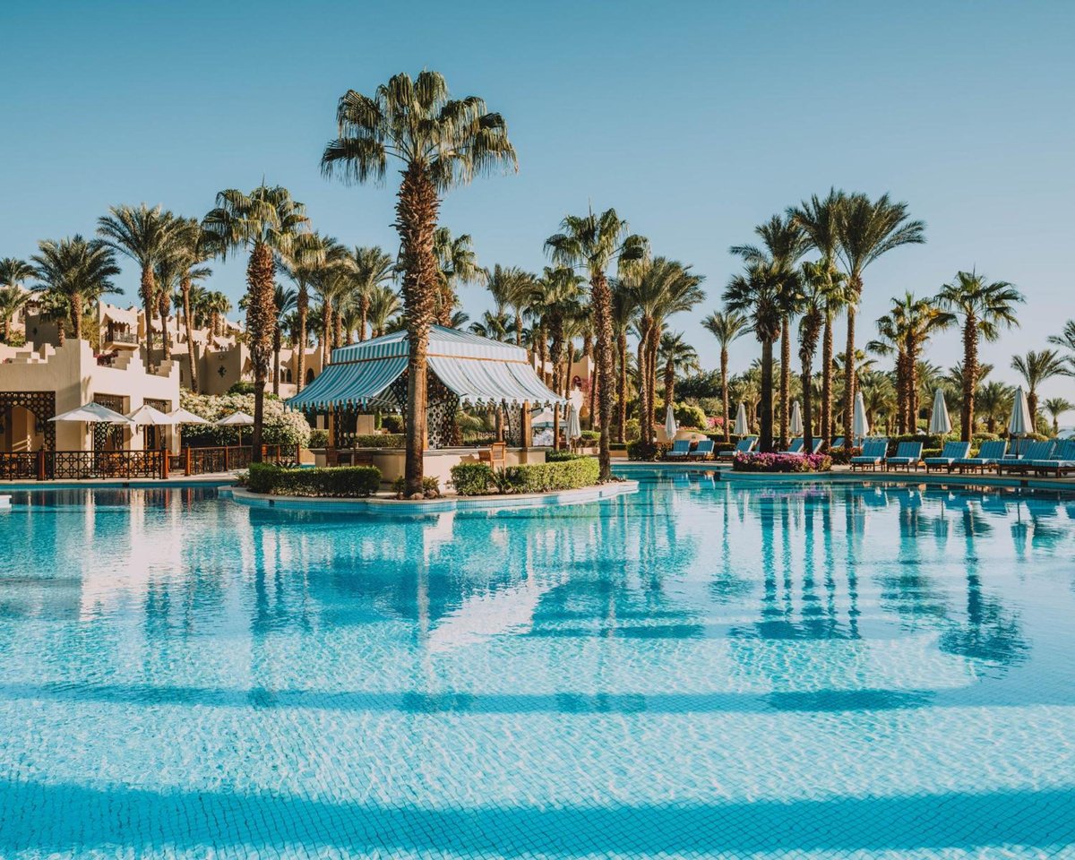 Four Seasons Resort Sharm El Sheikh pool with a palm-lined island and turquoise water.