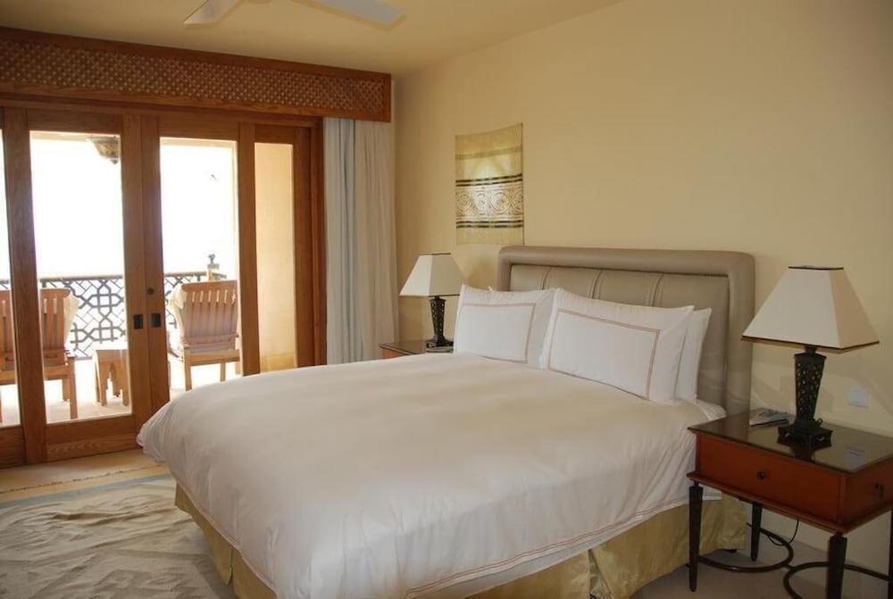 Four Seasons Resort Sharm El Sheikh bedroom with a large bed and wooden balcony doors.