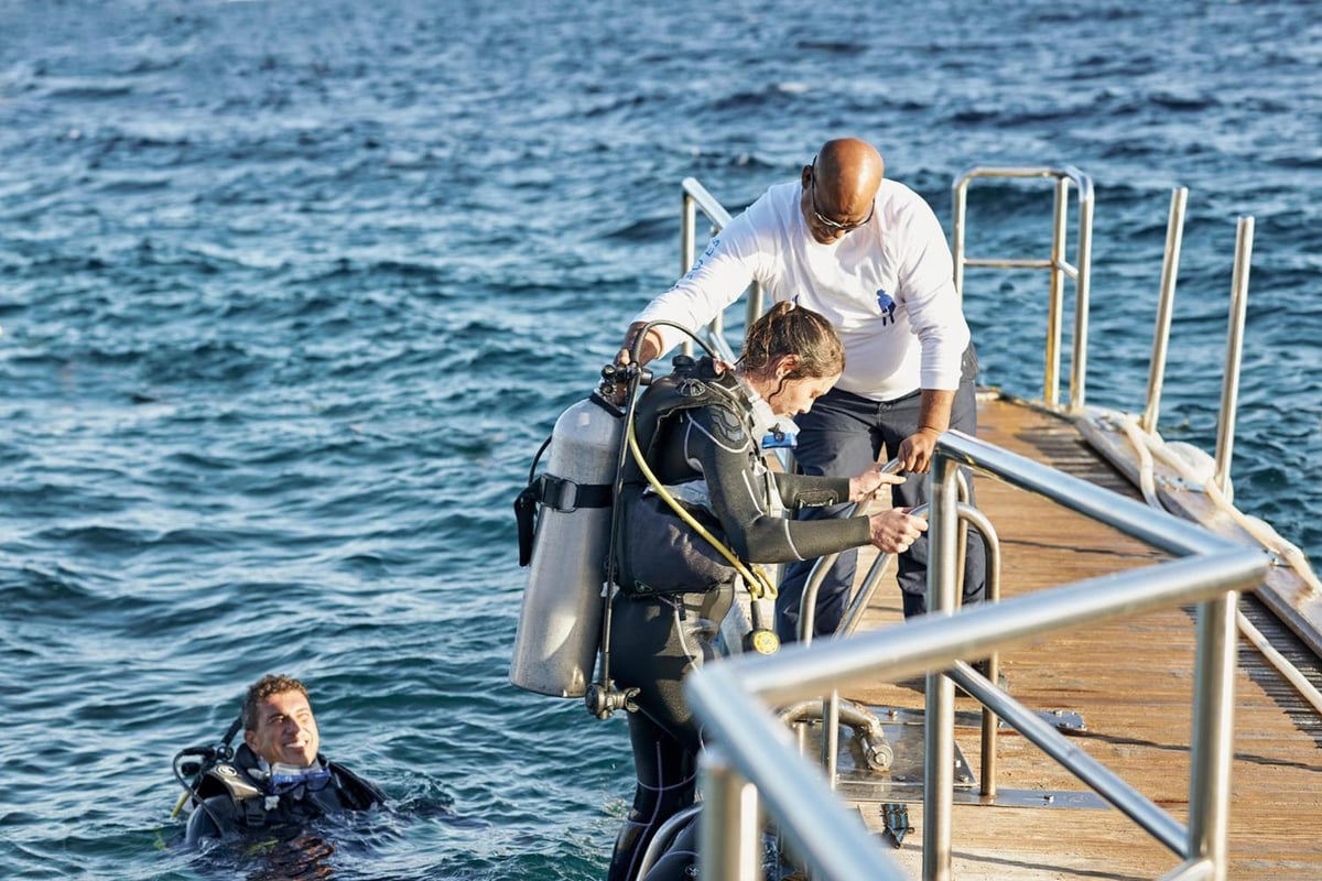 Four Seasons Resort Sharm El Sheikh dive pier with a diver boarding and another diver in the water.