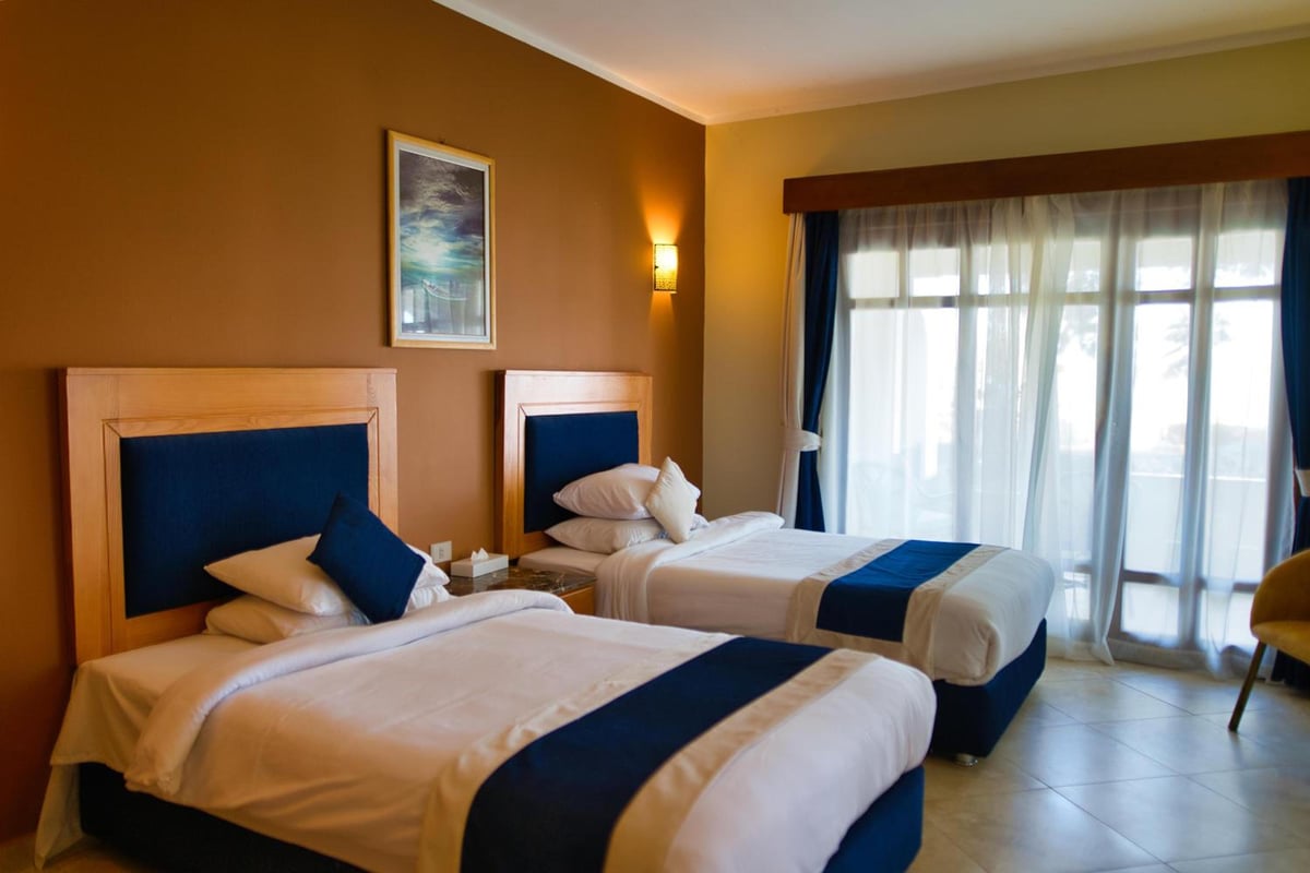 Tropitel Dahab Oasis twin bedroom with two beds and large windows.