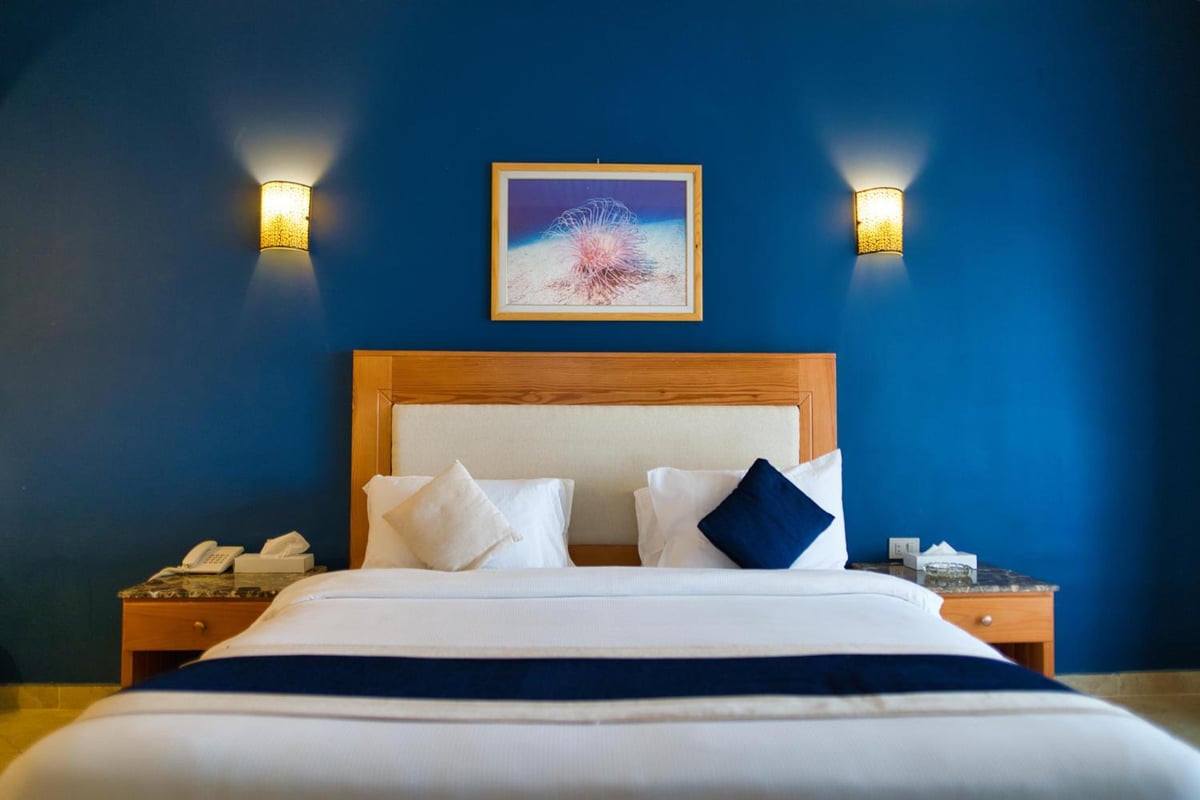 Tropitel Dahab Oasis bedroom with a wooden headboard and blue walls.