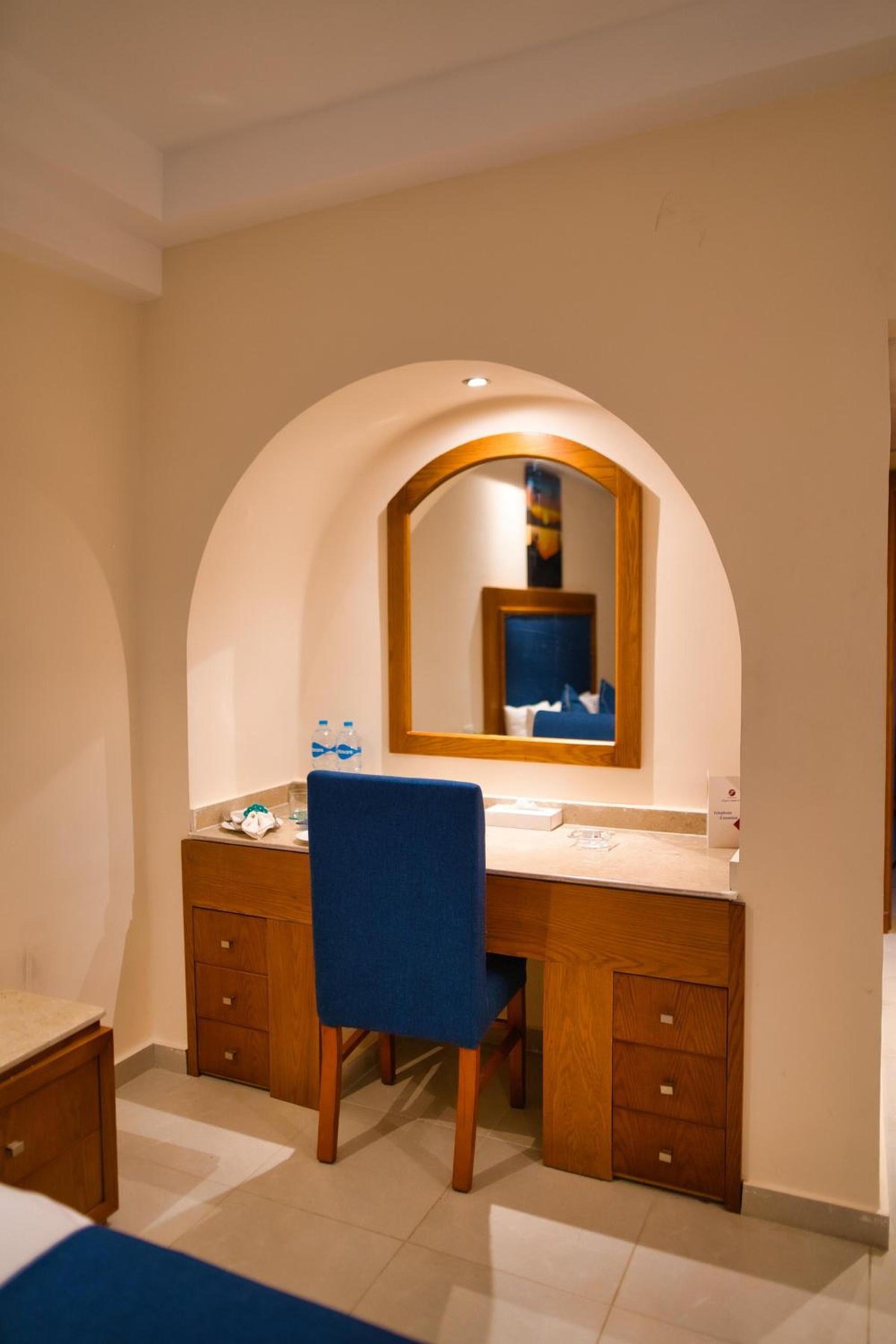 Tropitel Dahab Oasis guest room vanity with an arched mirror and blue chair.