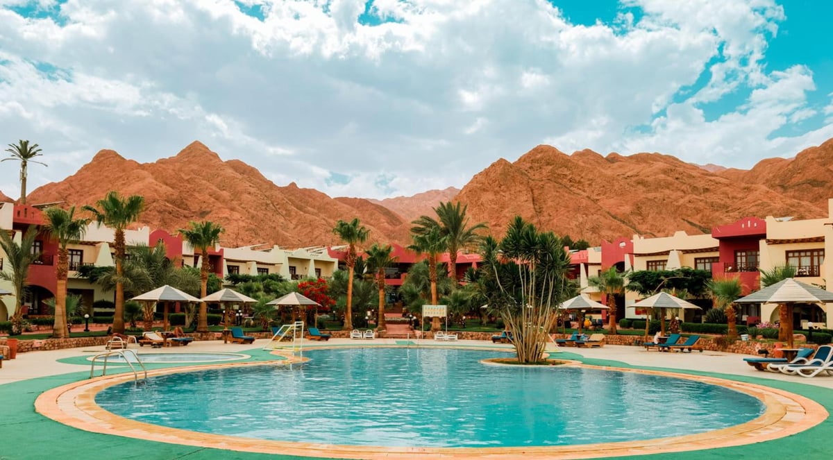 Tropitel Dahab Oasis pool with curved edges and a mountain backdrop.