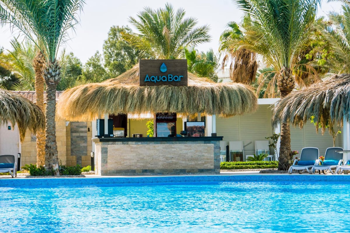 Sunrise Aqua Joy Resort poolside bar with a thatched roof and a swimming pool.