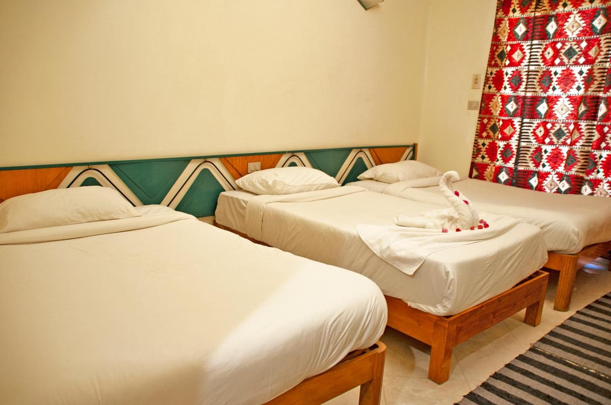 New Memnon Hotel Luxor guest room with three beds and patterned curtains.