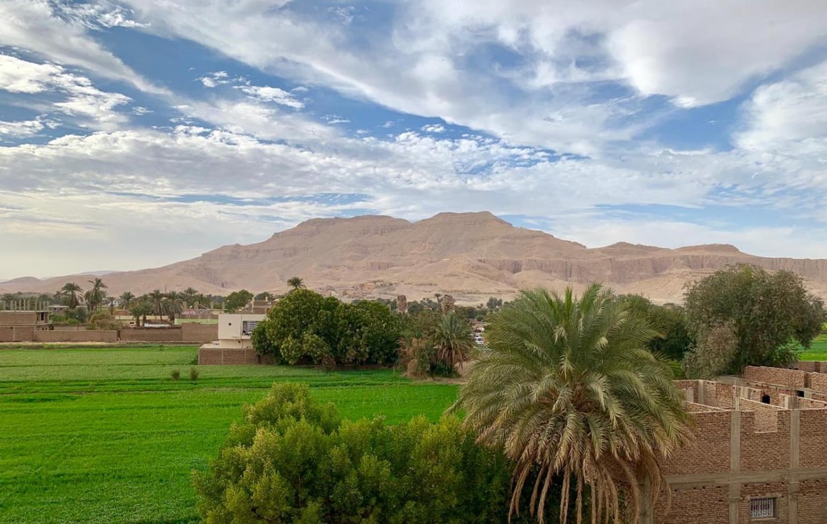 New Memnon Hotel Luxor mountain view with green fields and distant mountains.