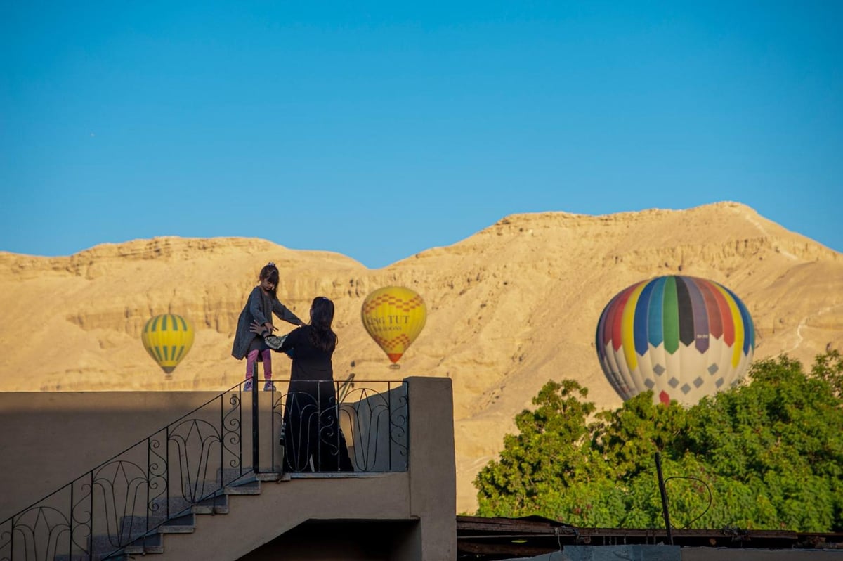 New Memnon Hotel Luxor roof terrace with hot air balloons and desert hills.