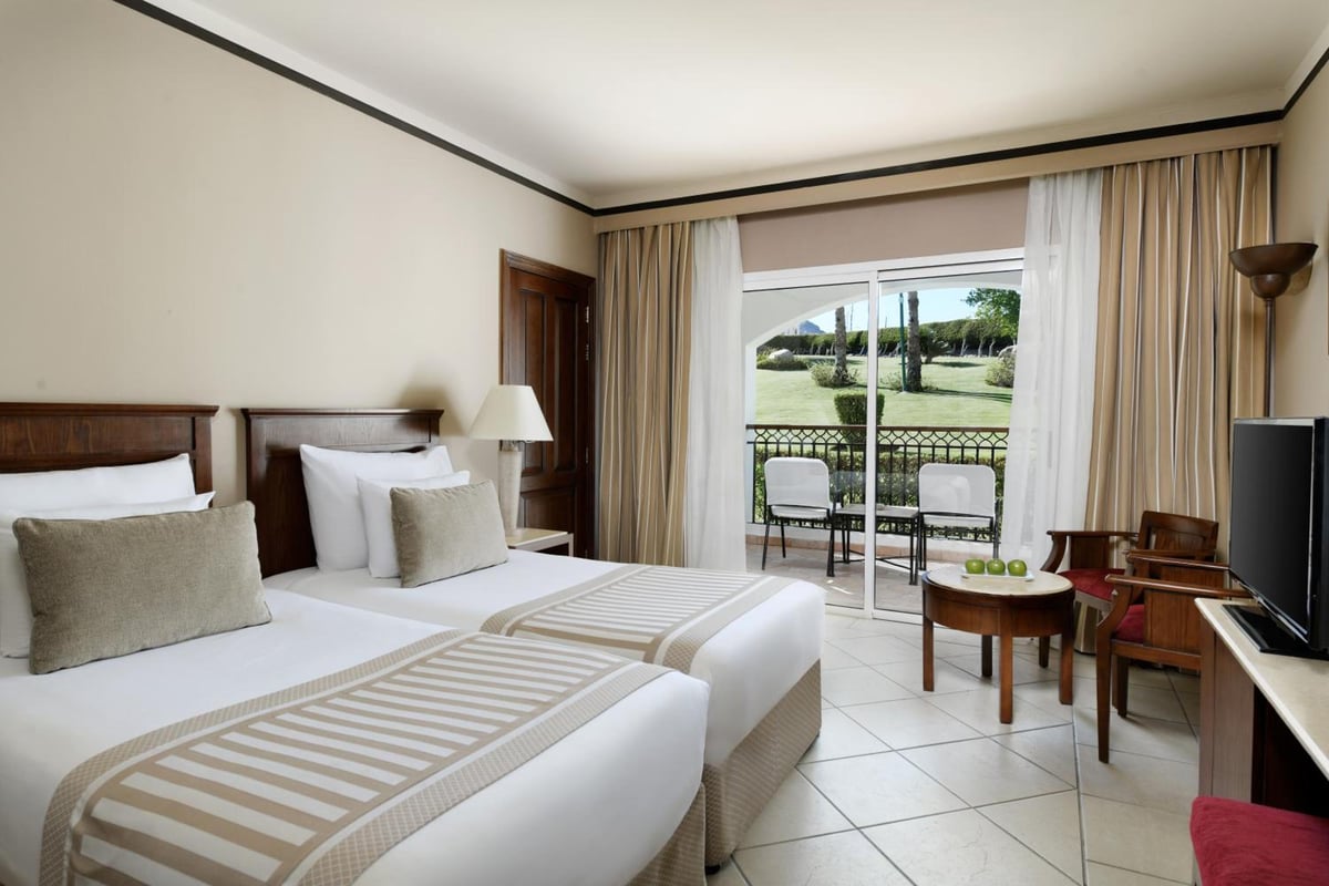 JAZ Dahabeya twin bedroom with two beds and sliding doors to a balcony.