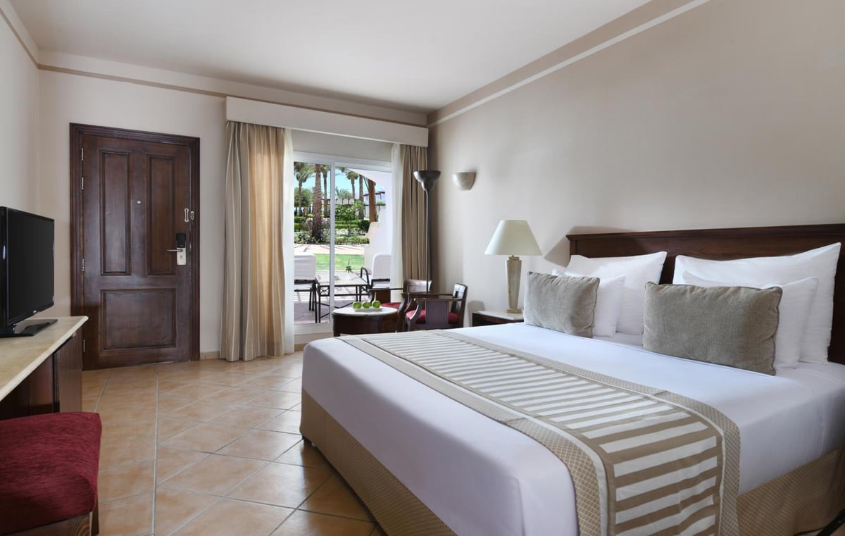 JAZ Dahabeya bedroom with a white bed and sliding glass doors.