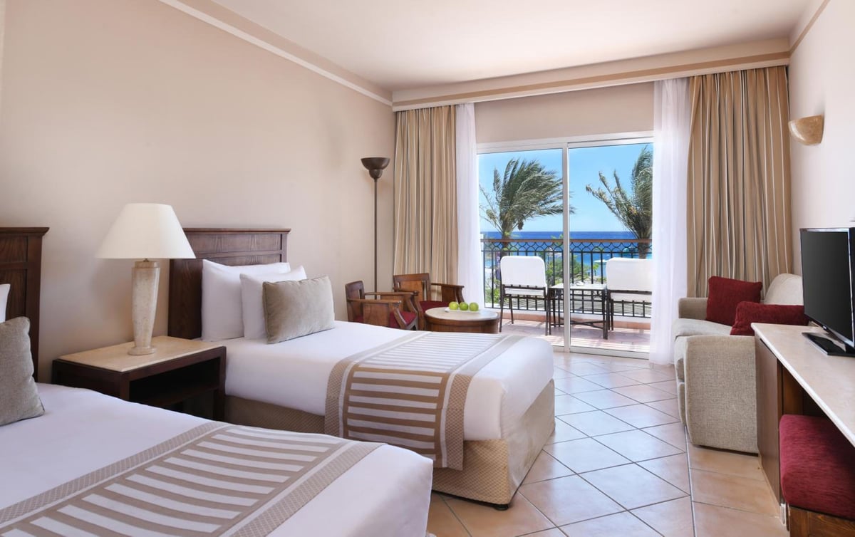 JAZ Dahabeya twin bedroom with two beds and sliding glass doors.