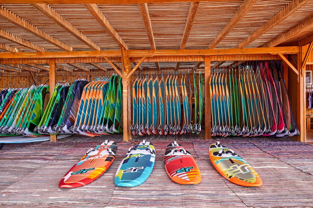 JAZ Dahabeya board storage with a wooden rack and colorful boards.