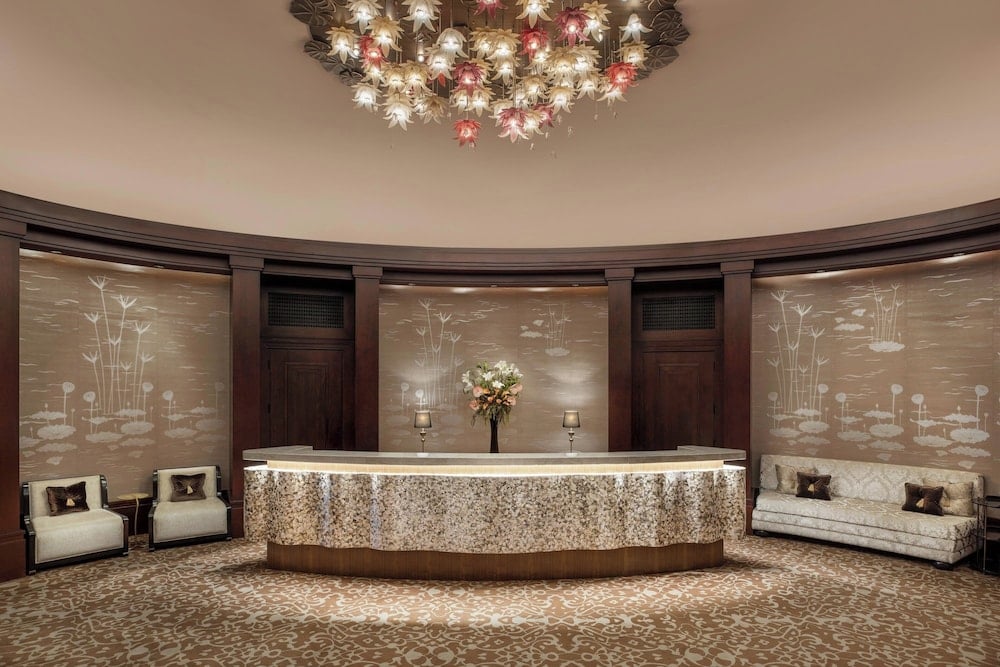 St. Regis Cairo lobby with curved reception desk and floral chandelier.