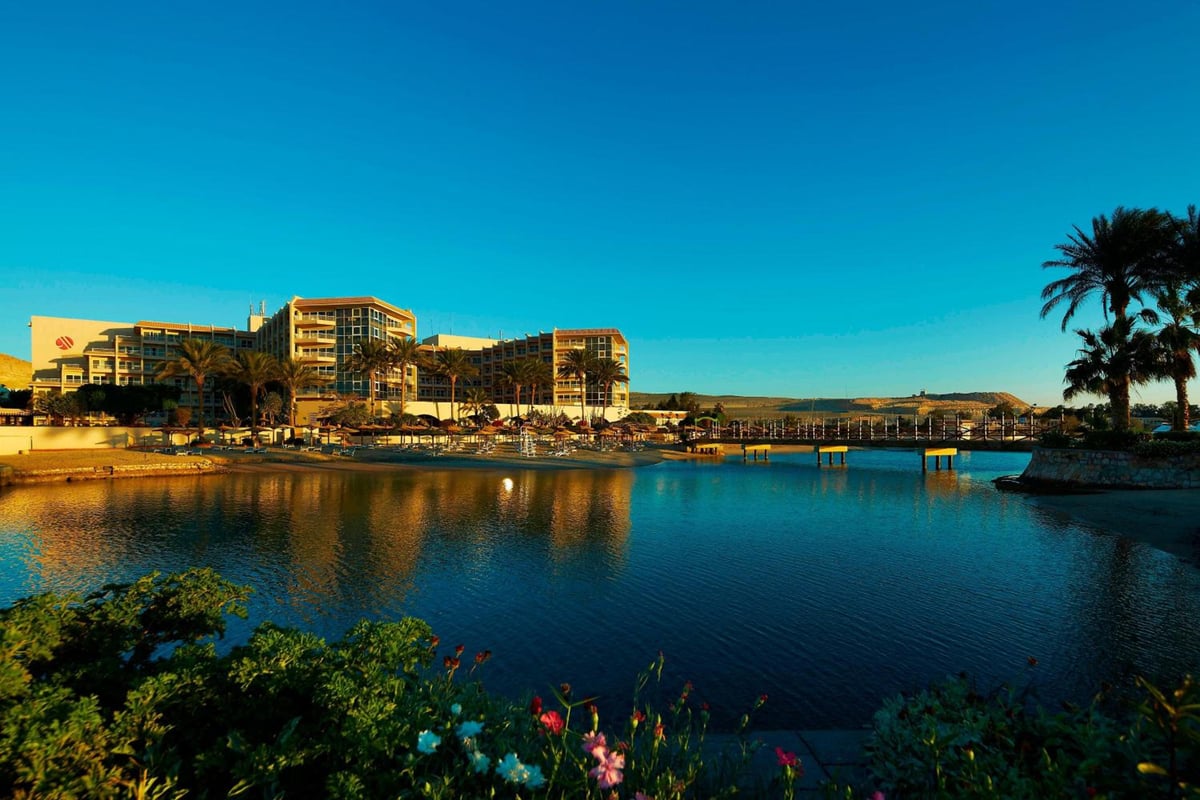 Marriott Hurghada Beach Resort exterior with waterside lagoon and palm trees.