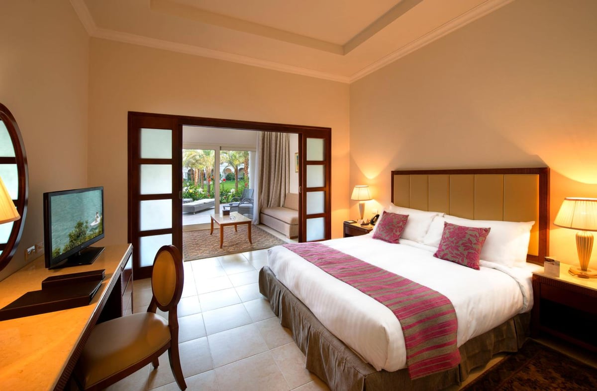 Baron Palace Sahl Hasheesh bedroom with a large bed and open doors to a terrace.