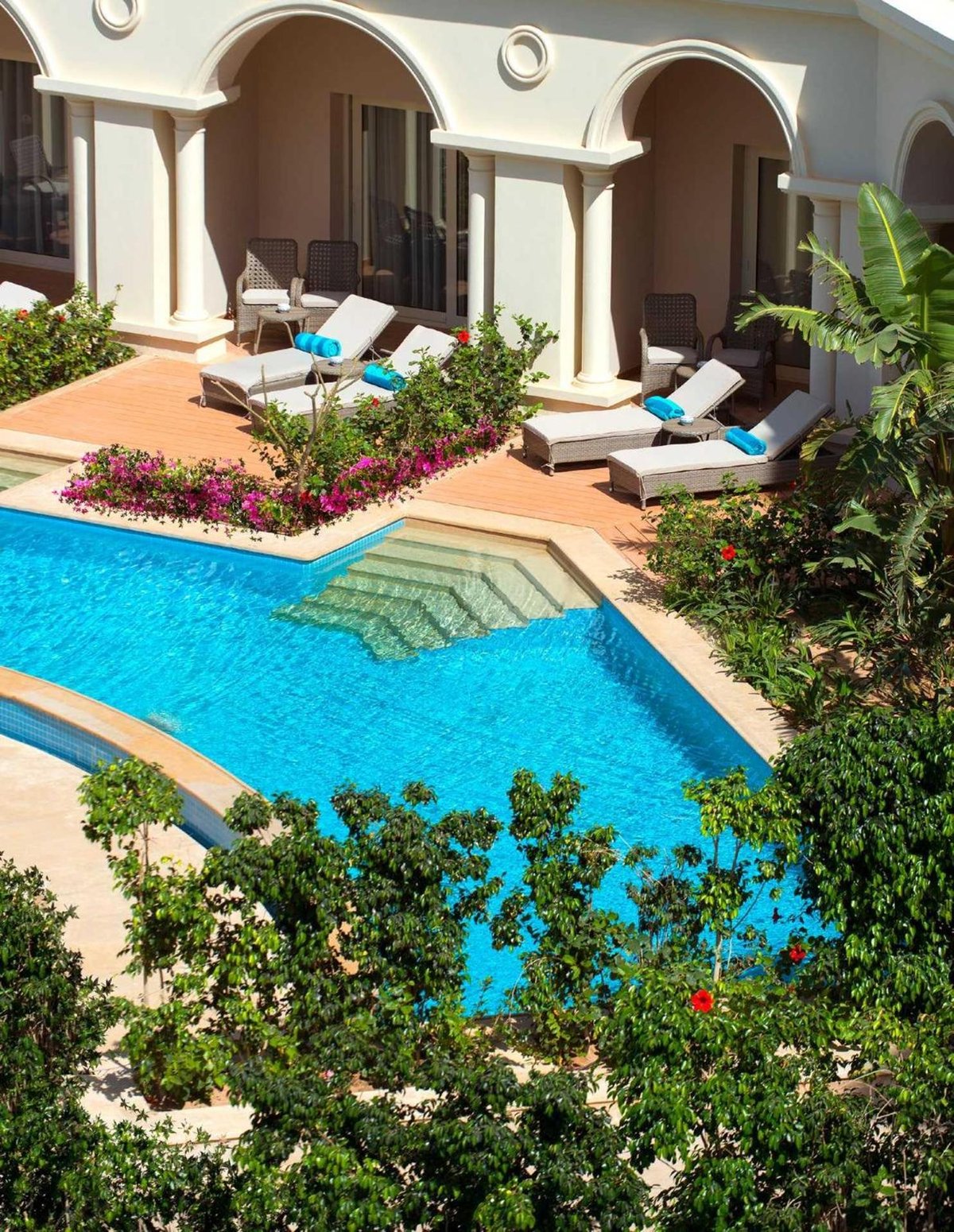 Baron Palace Sahl Hasheesh pool terrace with arched doorways and poolside seating.