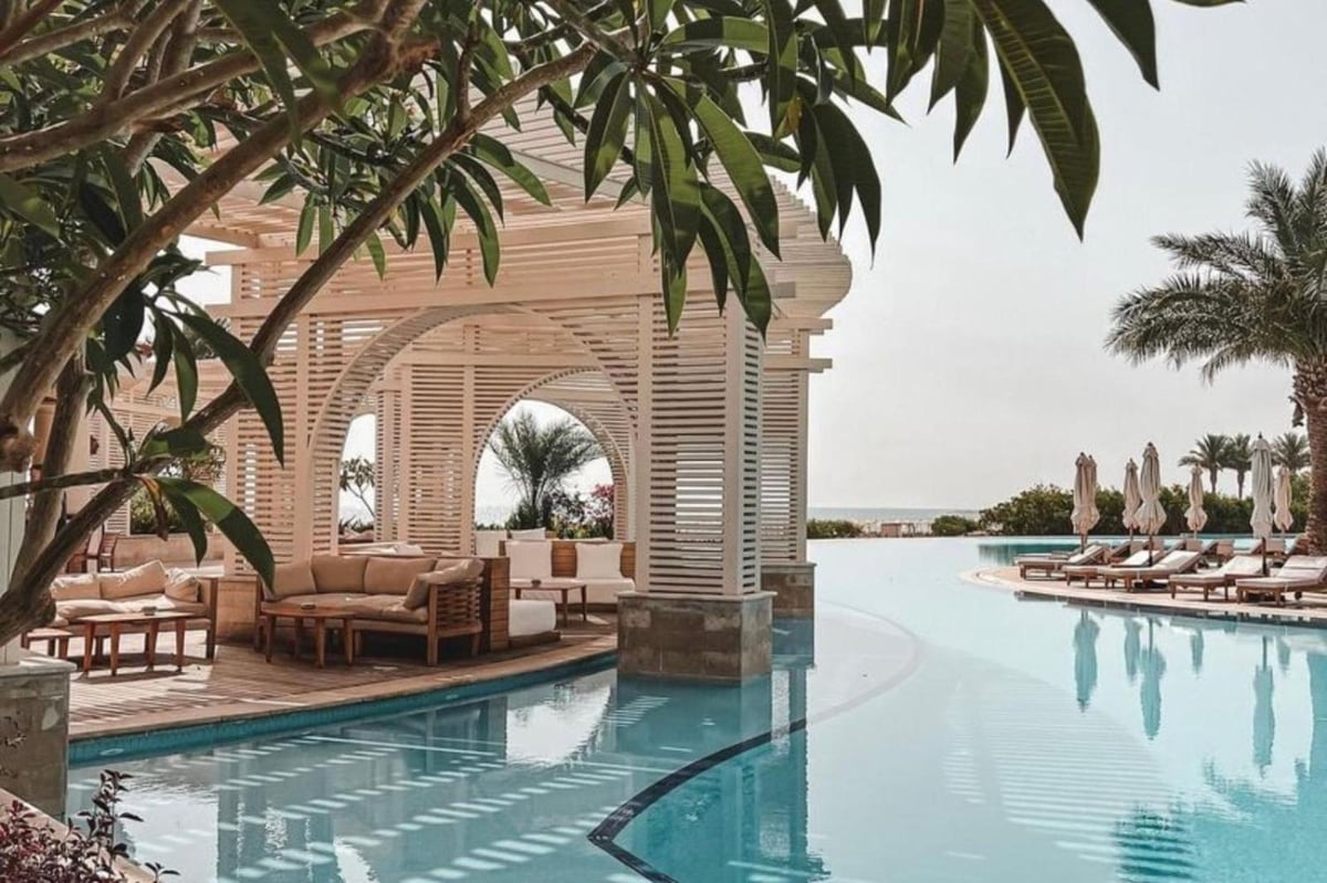 Baron Palace Sahl Hasheesh outdoor pool with a slatted pergola and curved edge.