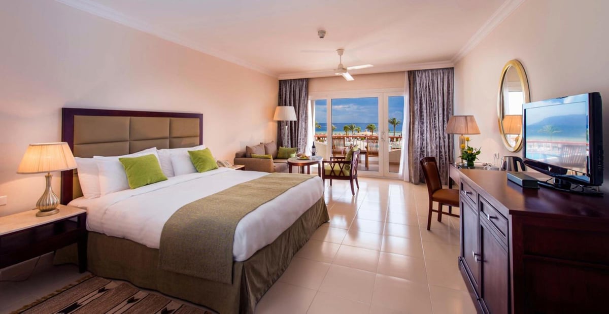 Baron Resort Sharm El Sheikh hotel bedroom with a large bed and sliding glass doors.