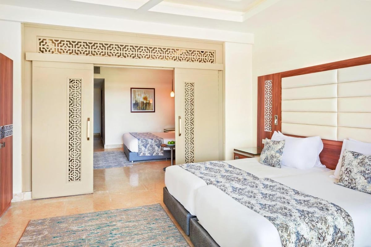 Pickalbatros Sea World Resort Marsa Alam bedroom with a white bed and decorative sliding doors.