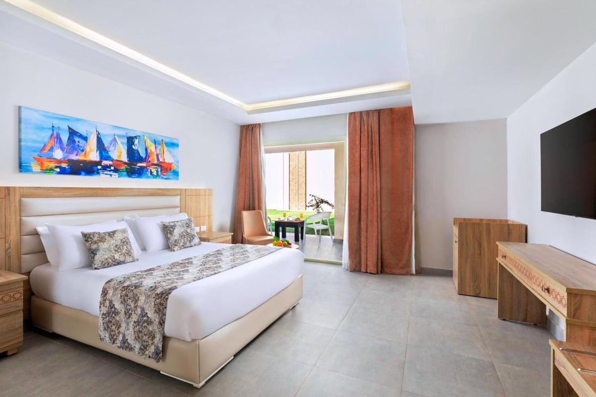 Pickalbatros Sea World Resort Marsa Alam guest bedroom with a large bed and sliding glass doors.