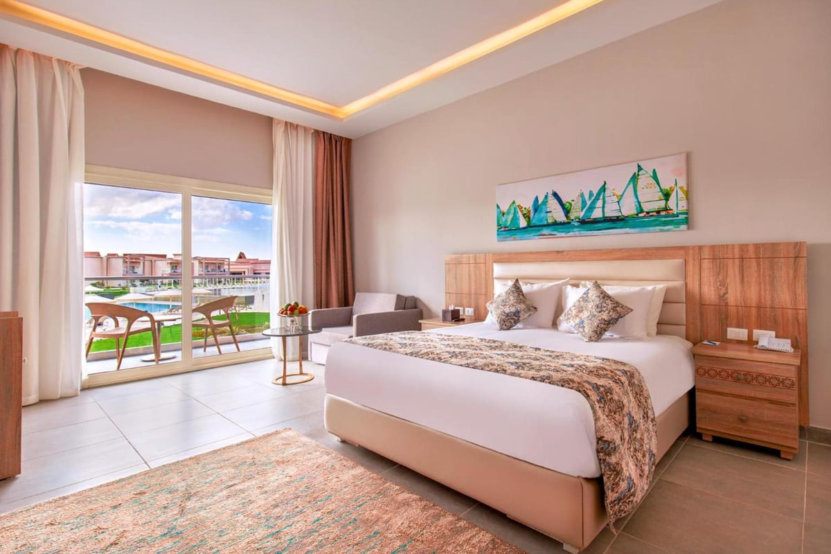 Pickalbatros Sea World Resort Marsa Alam bedroom with a large bed and balcony doors.