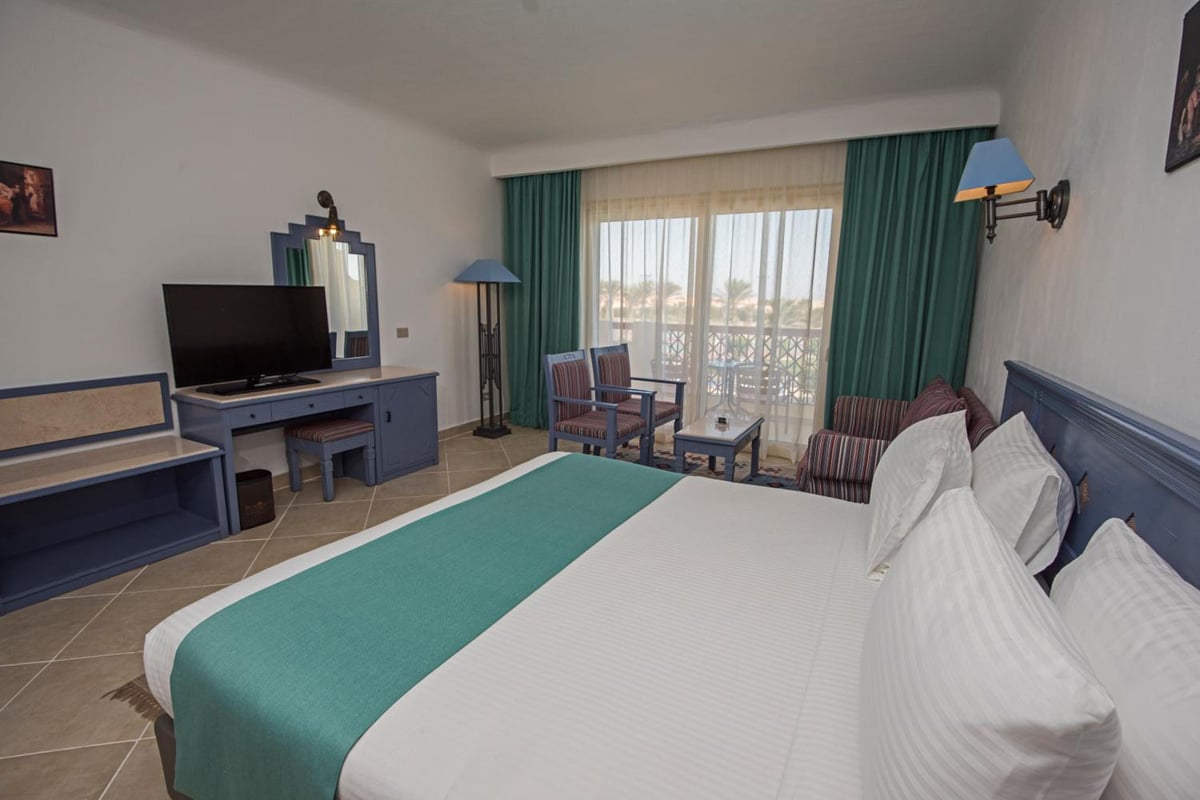 Sunrise Royal Makadi Resort bedroom with a large bed and sliding glass doors.
