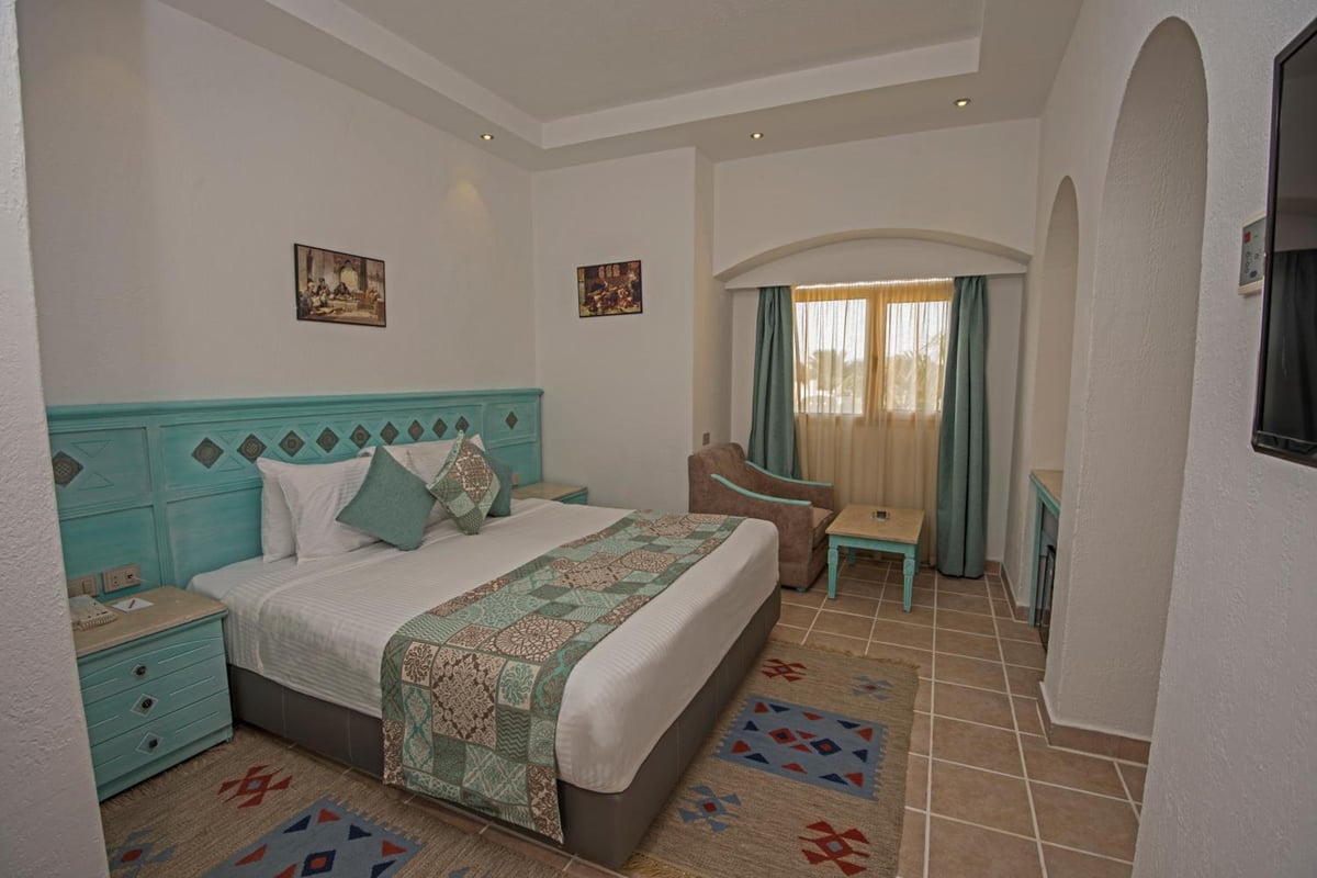 Sunrise Royal Makadi Resort guest room with a turquoise headboard and curtained sitting area.