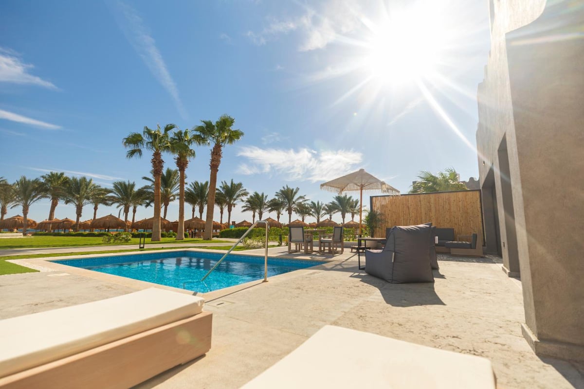 Sunrise Royal Makadi Resort pool deck with a swimming pool and palm trees.