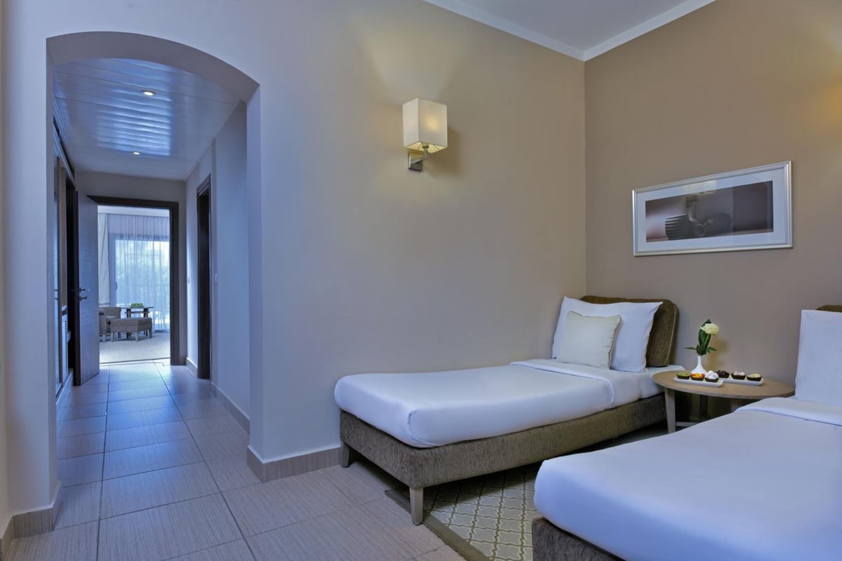 Steigenberger Alcazar guest room with two single beds and an arched hallway.