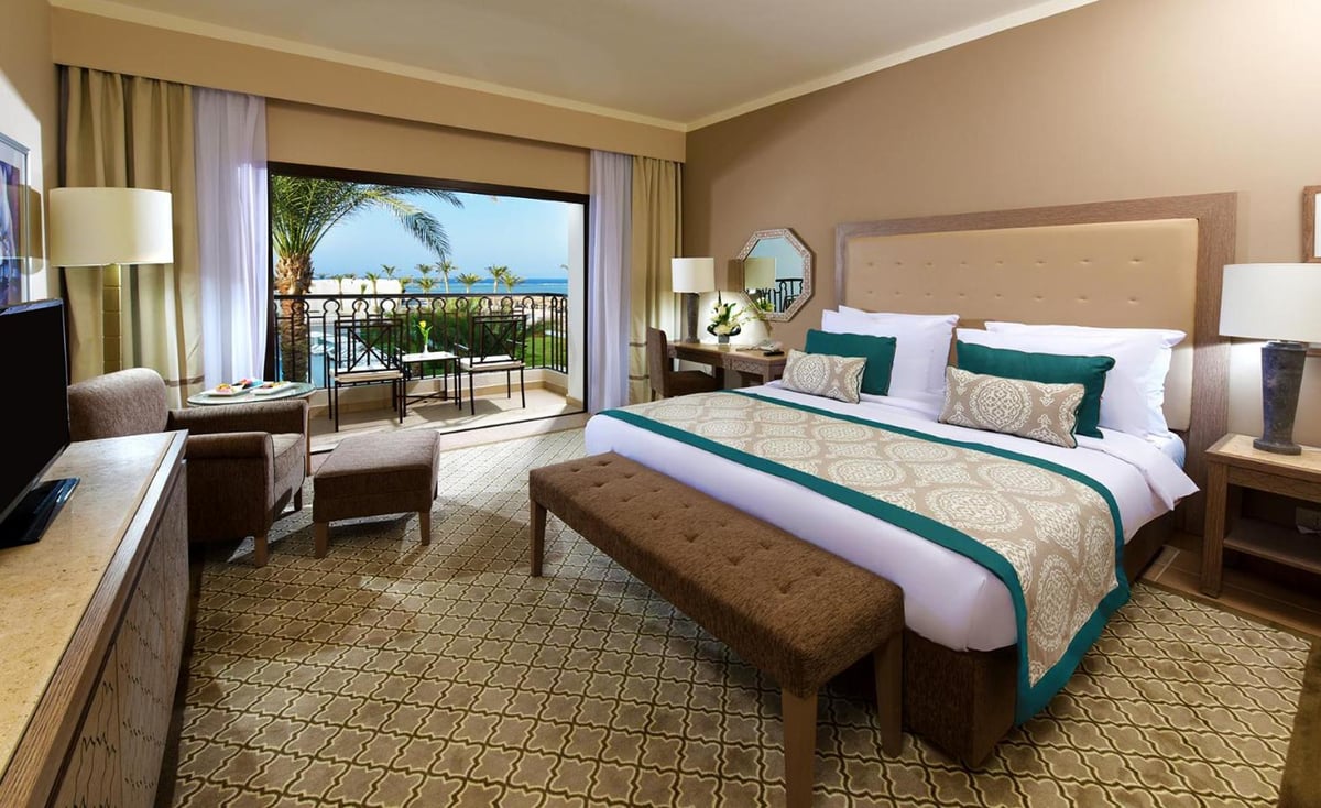 Steigenberger Alcazar bedroom with a king bed and a balcony overlooking the sea.