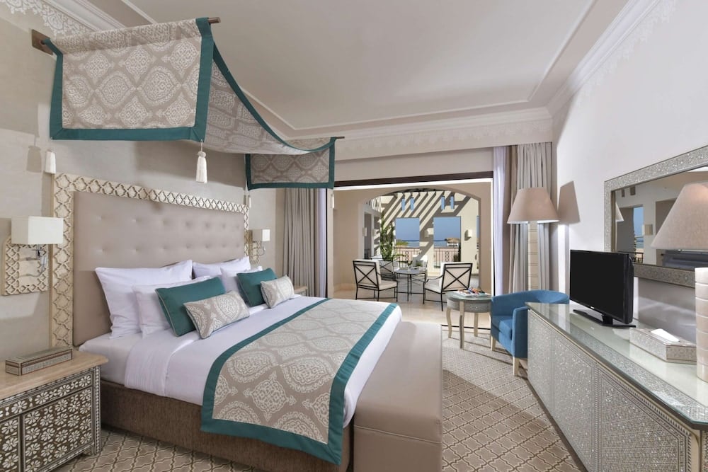 Steigenberger Alcazar guest room with a canopy bed and a seating area.
