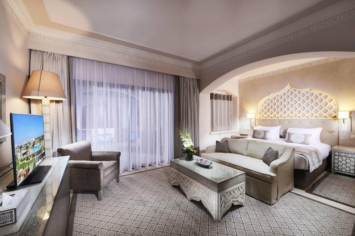 Steigenberger Alcazar guest room with an arched headboard and a sitting area.