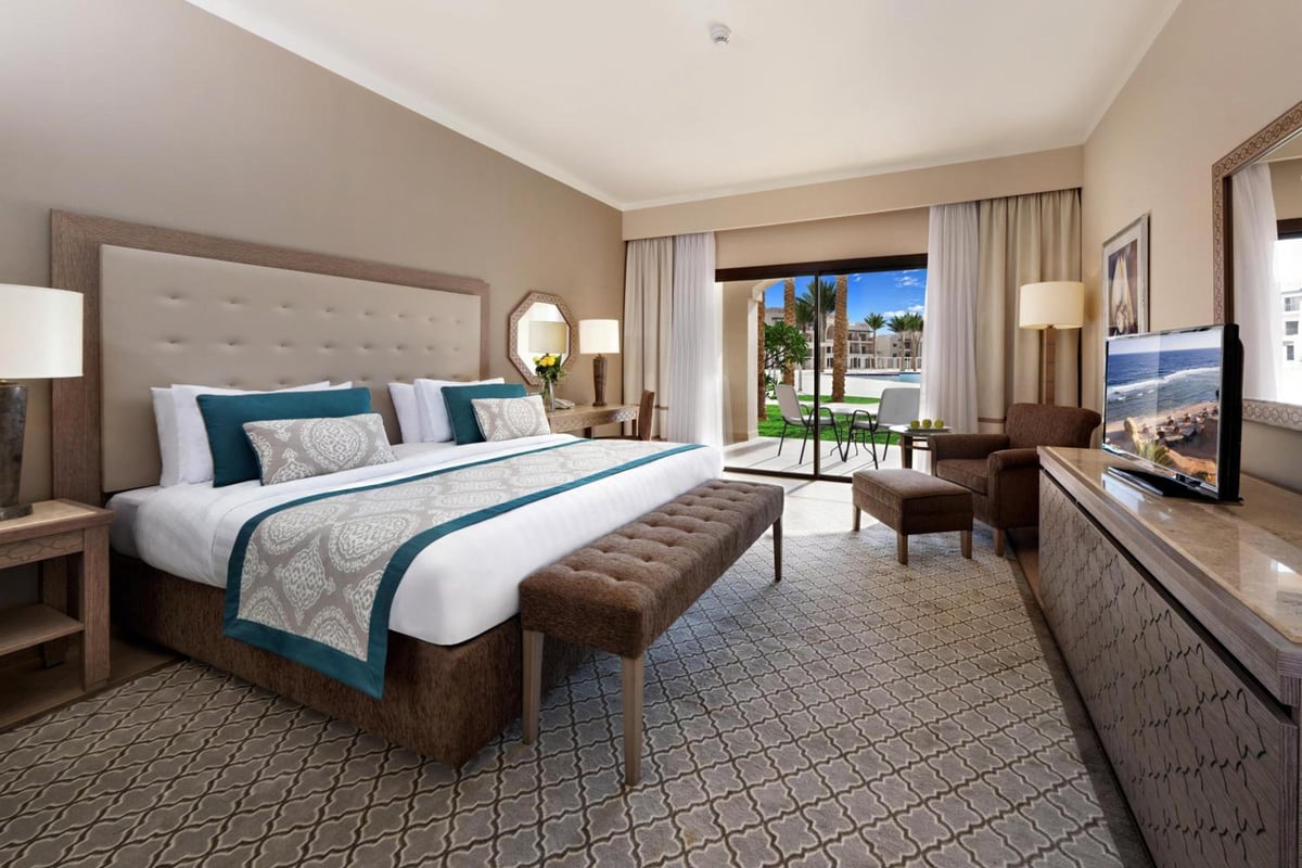 Steigenberger Alcazar guest bedroom with a large bed and doors opening to a patio.