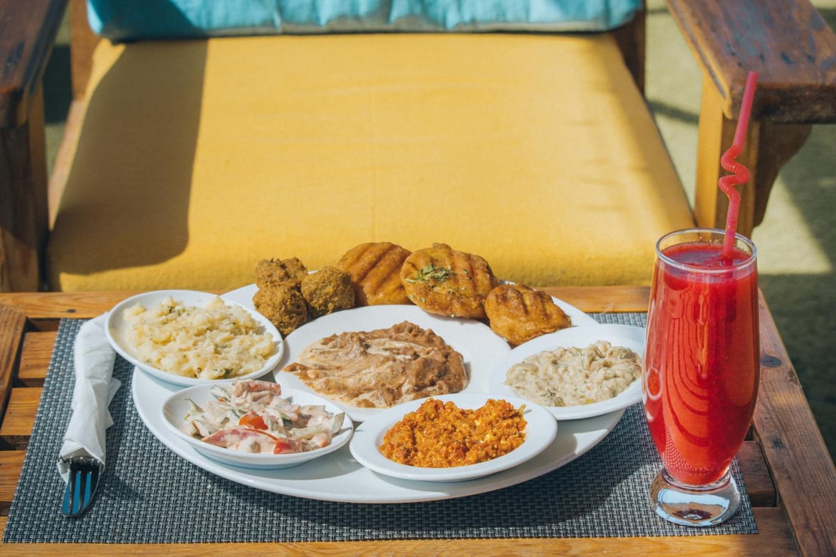 Swiss Royal Dahab dining table with a plate of assorted food and a red drink.