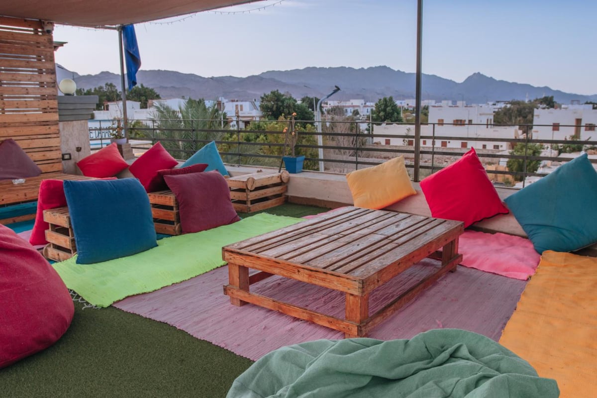 Swiss Royal Dahab terrace lounge with colorful floor cushions and mountain views.