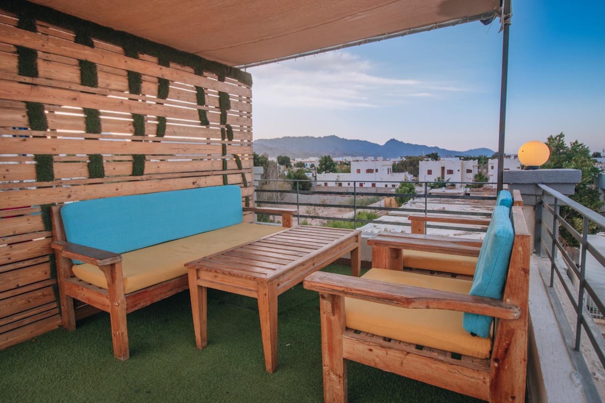 Swiss Royal Dahab terrace with wooden seating and a view of distant hills.