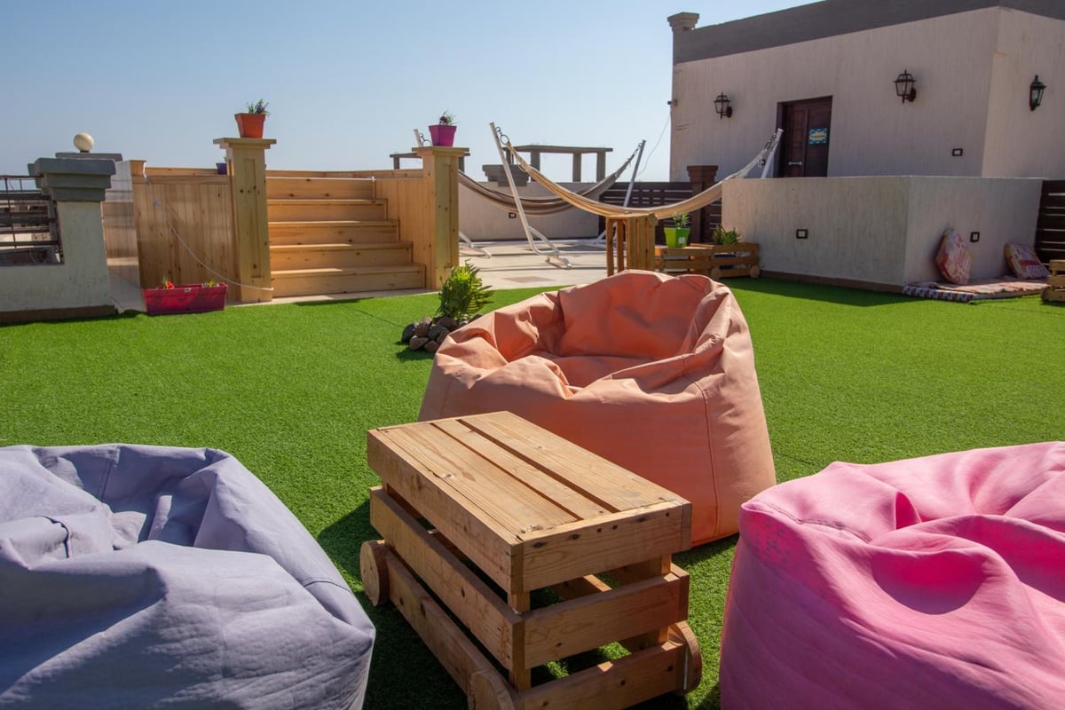 Swiss Royal Dahab rooftop lounge with artificial grass and a hammock.
