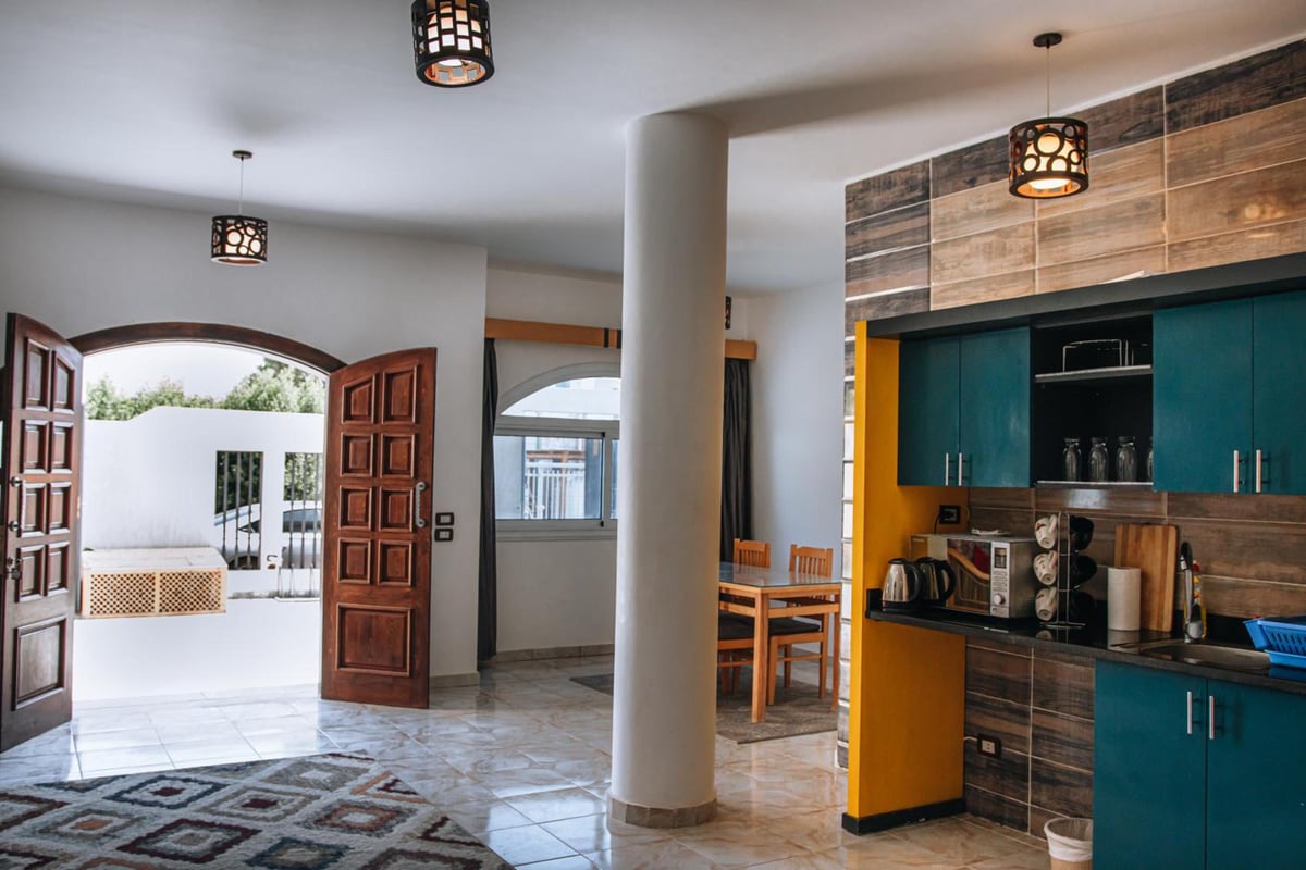 Swiss Royal Dahab kitchen dining area with teal cabinets and a wooden dining table.