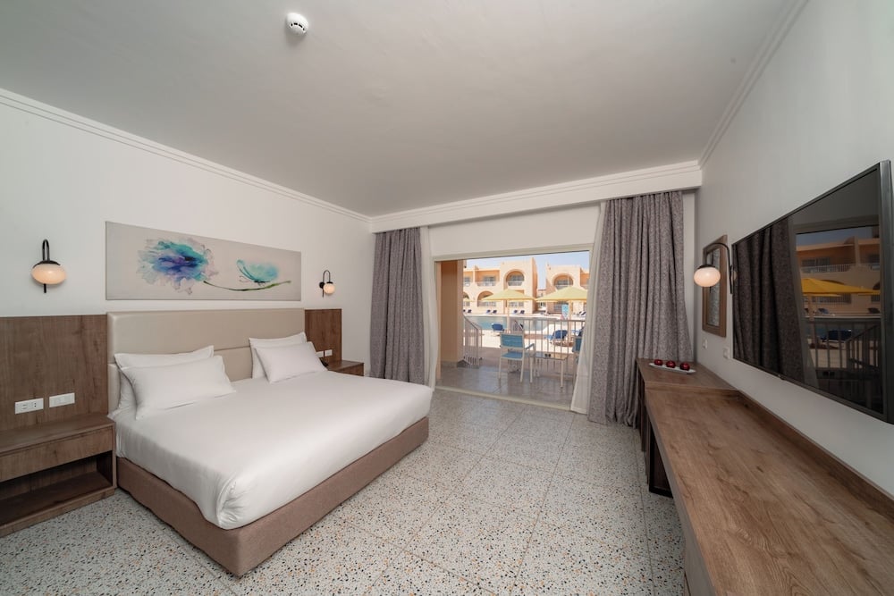 Pickalbatros Vita Resort Portofino guest room with a double bed and sliding doors to a balcony.